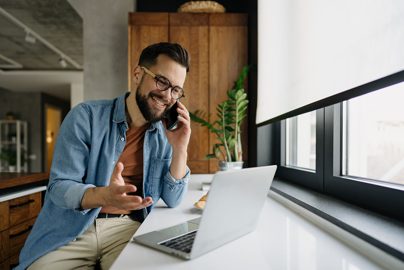 Man talking on phone with laptop in front of him